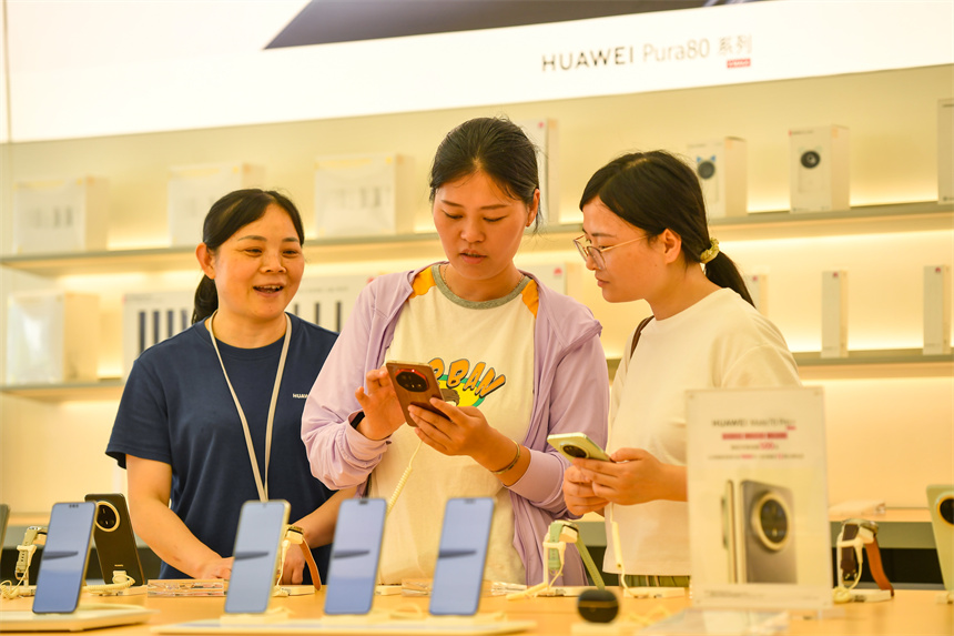 導購員正在向消費者介紹手機功能。周亮攝