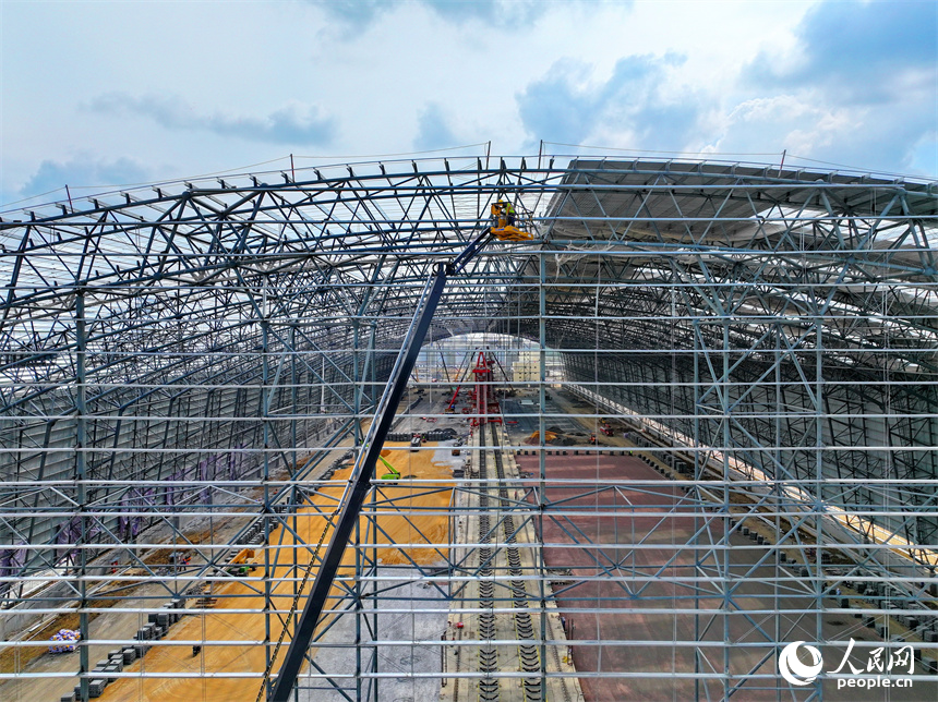 建設者們冒著高溫在高空進行貨棚擋板安裝作業。人民網 朱海鵬攝