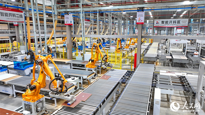 贛州市南康區國際家居總部經濟區的一家企業全屋整裝智能制造車間內，工人在操作智能機器人手臂裁切家具板材。人民網 朱海鵬攝