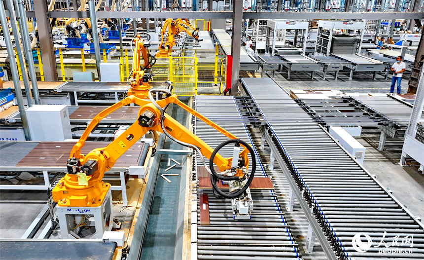 贛州市南康區國際家居總部經濟區的一家企業全屋整裝智能制造車間內，工人在操作智能機器人手臂裁切家具板材。人民網 朱海鵬攝