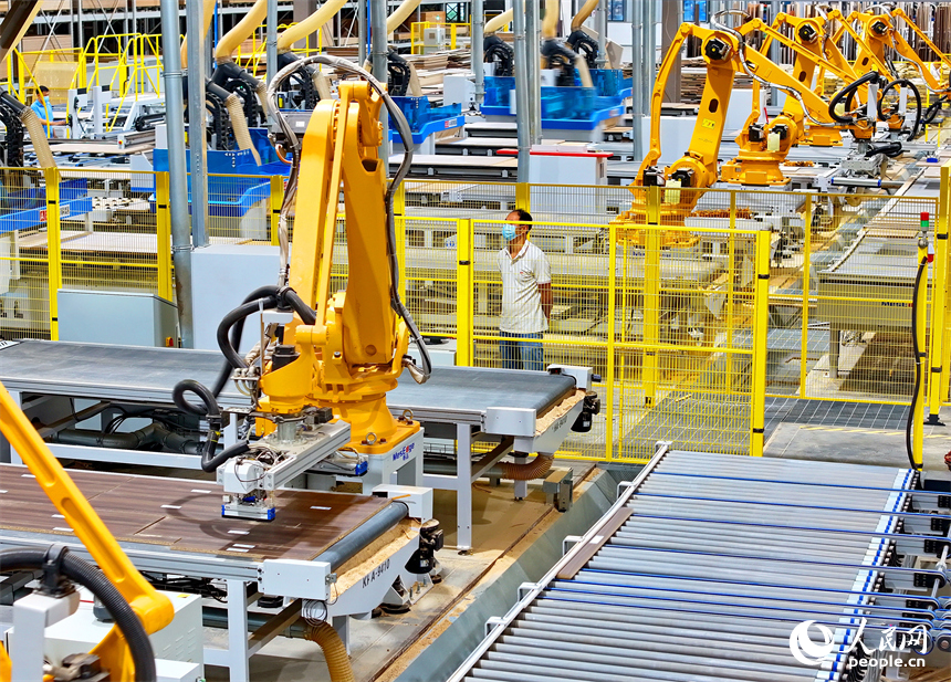 贛州市南康區國際家居總部經濟區的一家企業全屋整裝智能制造車間內，工人在操作智能機器人手臂裁切家具板材。人民網 朱海鵬攝