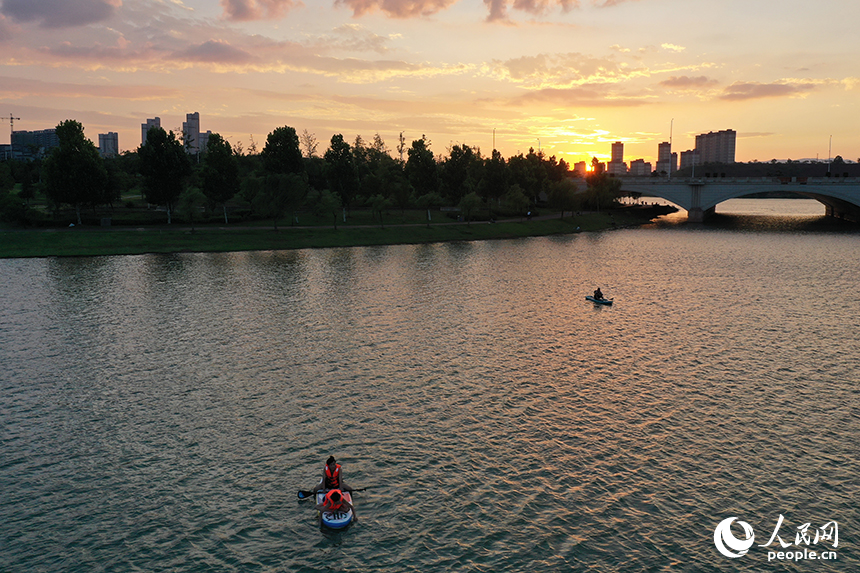 夕陽下，紅谷灘區九龍湖泛著金色波光，槳板愛好者們正在湖面揮槳劃行。人民網記者 時雨攝