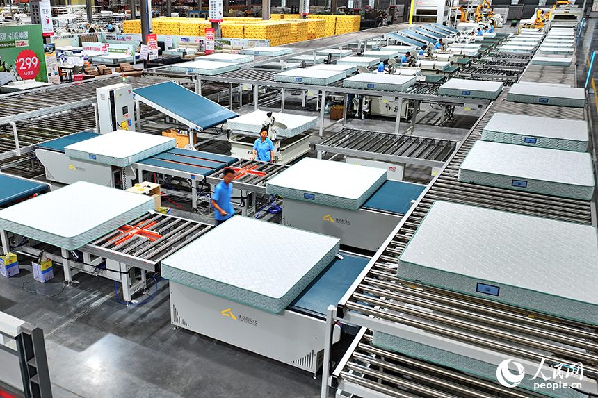 贛州市南康區的A家家居數字化智能制造基地，機械臂、傳輸機循環作業，工人在智能床墊生產線上趕制訂單產品。人民網 朱海鵬攝