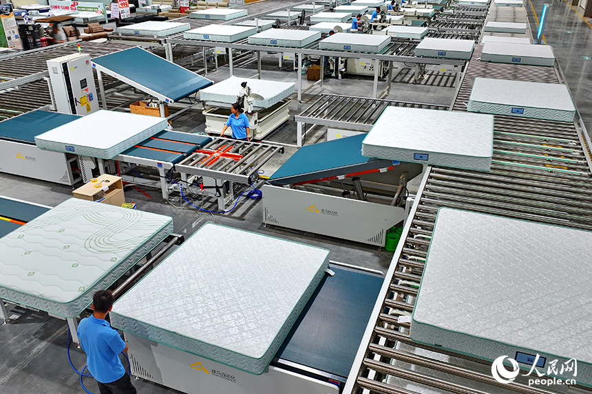 贛州市南康區的A家家居數字化智能制造基地，機械臂、傳輸機循環作業，工人在智能床墊生產線上趕制訂單產品。人民網 朱海鵬攝