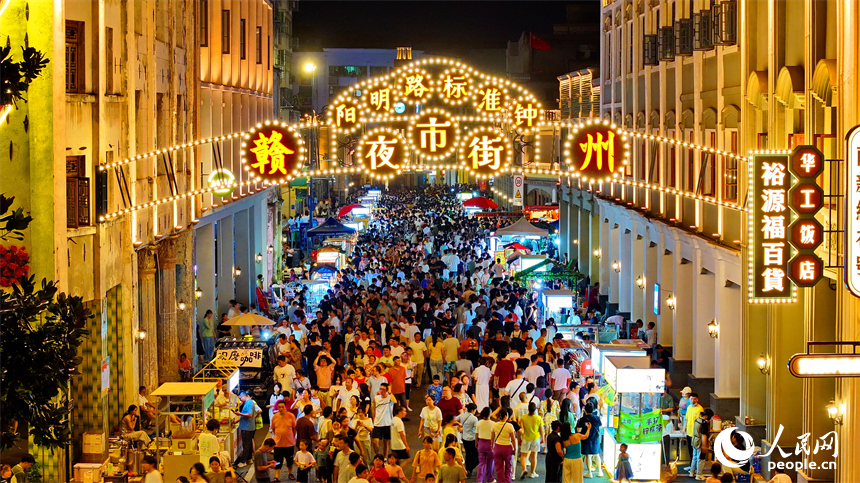 贛州市陽明路標準鐘夜市街，人頭攢動、熙熙攘攘，許多游客在逛夜市、吃小吃。人民網 朱海鵬攝