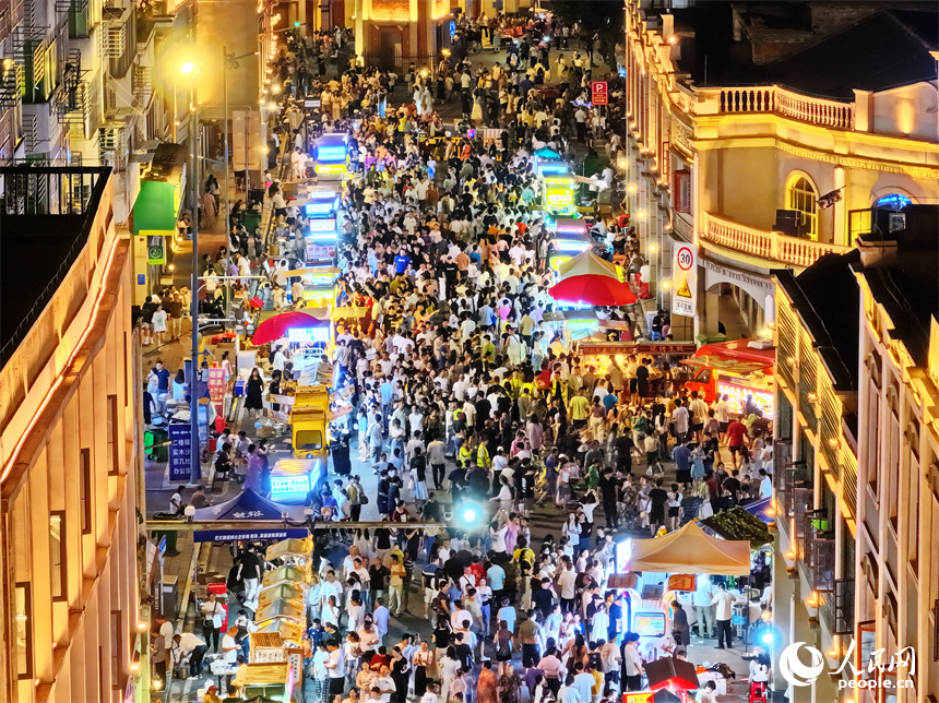 贛州市陽明路標準鐘夜市街，人頭攢動、熙熙攘攘，許多游客在逛夜市、吃小吃。人民網 朱海鵬攝