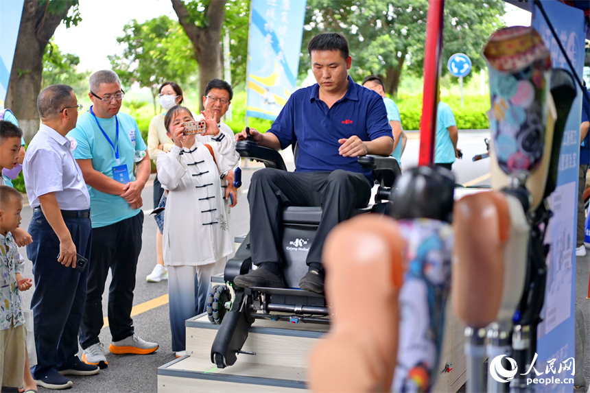 參觀者在科技助殘展區咨詢試用無障礙爬樓機器人產品。人民網 朱海鵬攝