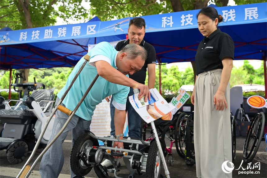 殘障人士在科技助殘展區咨詢試用智能電動輪椅產品。人民網 朱海鵬攝