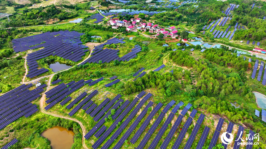 撫州市南豐縣萊溪鄉西山村“農光互補”光伏發電站，荒山坡上安裝的光伏板熠熠生輝，與綠樹青山相映相襯。人民網 朱海鵬攝