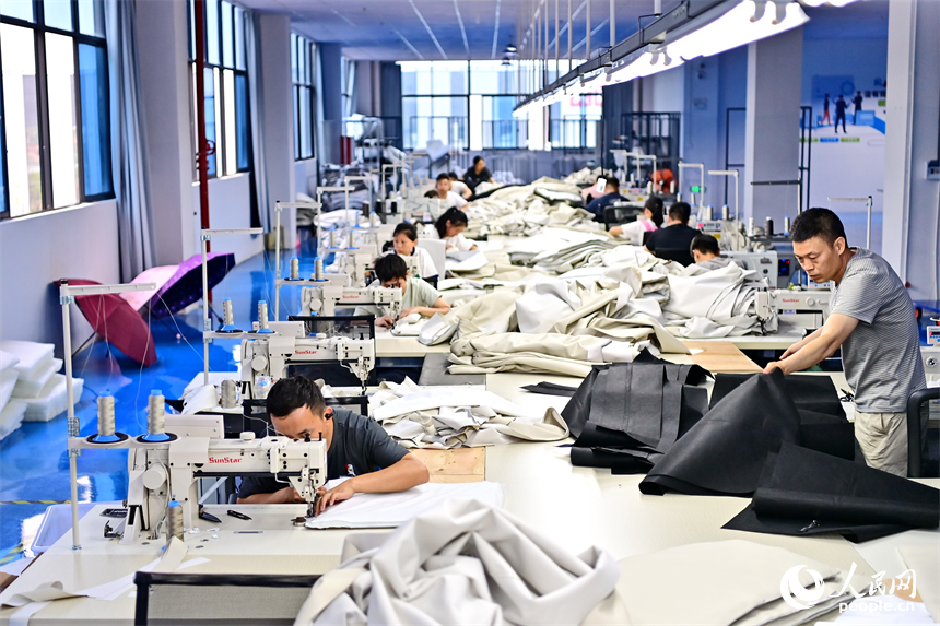 贛州市南康區的一家“工業上樓”項目家具生產企業內，工人在加工軟體家具。人民網 朱海鵬攝