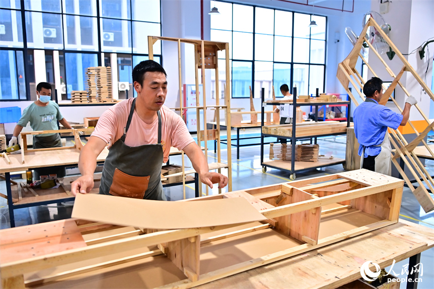 贛州市南康區的一家“工業上樓”項目家具生產企業內，工人在加工軟體家具。人民網 朱海鵬攝