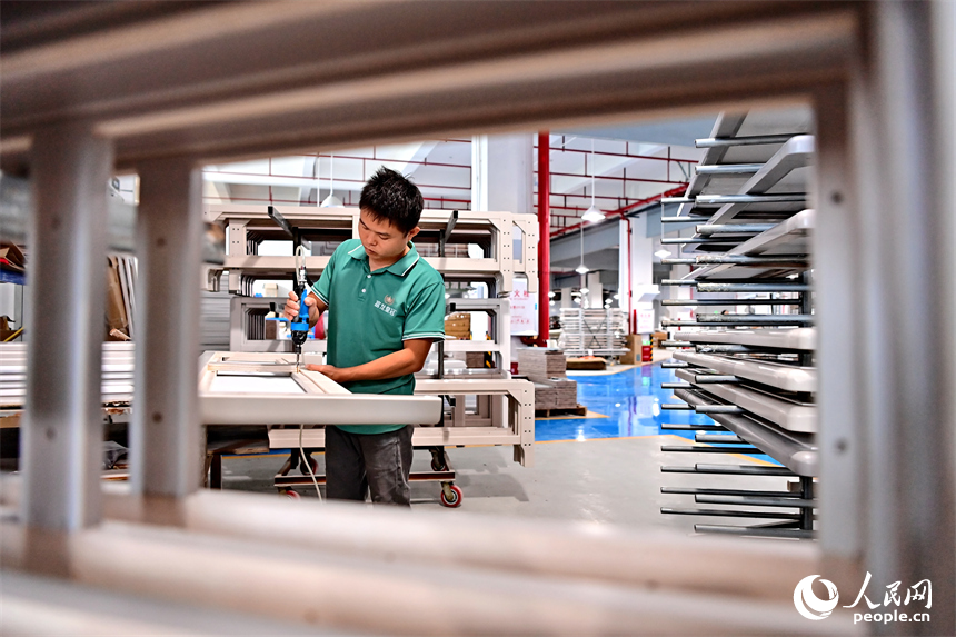 贛州市南康區的一家“工業上樓”項目家具生產企業內，工人在加工軟體家具。人民網 朱海鵬攝