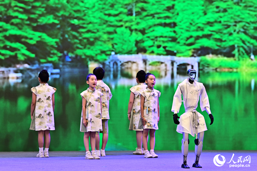 2025江西省網絡文明大會現場，人形機器人化身“詩人”，現場表演誦讀古詩詞，并與同臺表演者合影留念，讓觀眾耳目一新。人民網 朱海鵬攝