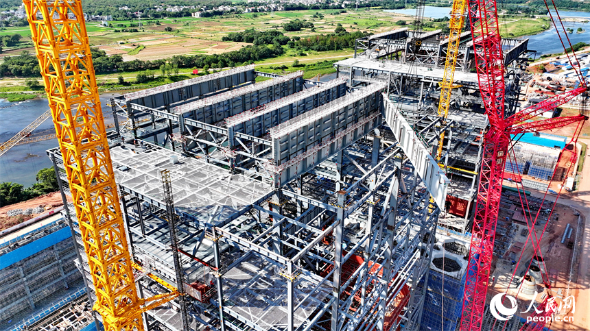 信豐電廠二期項目建設現場塔吊林立，施工作業有序，工人在吊裝鍋爐鋼結構設備。人民網 朱海鵬攝