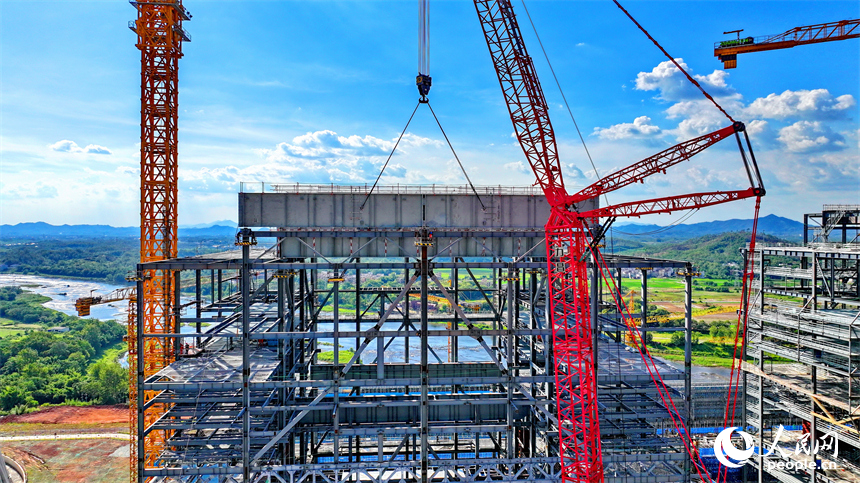 信豐電廠二期項目建設現場塔吊林立，施工作業有序，工人在吊裝鍋爐鋼結構設備。人民網 朱海鵬攝