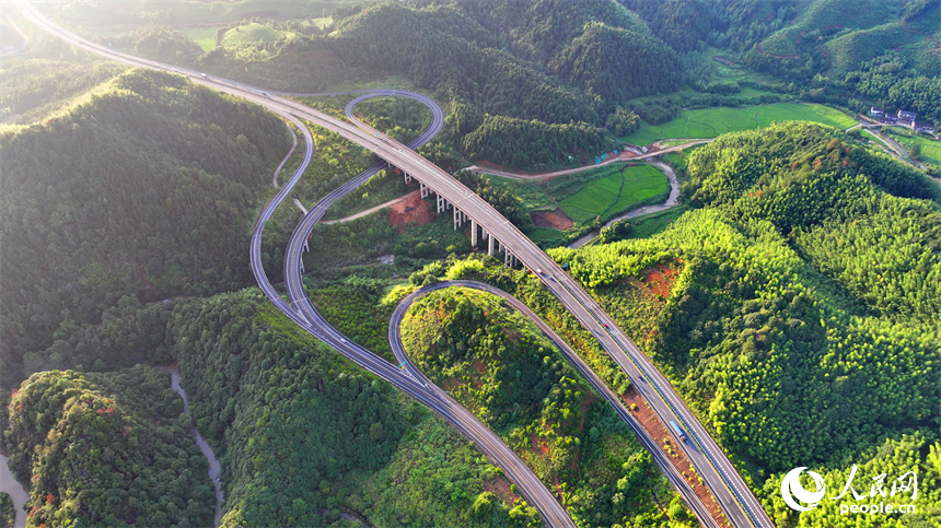 撫州市資溪縣嵩市鎮，撫（州）至吉（安）高速公路如同銀龍蜿蜒穿梭于蒼翠的崇山峻嶺間，與田園、村落相映成景。人民網 朱海鵬攝