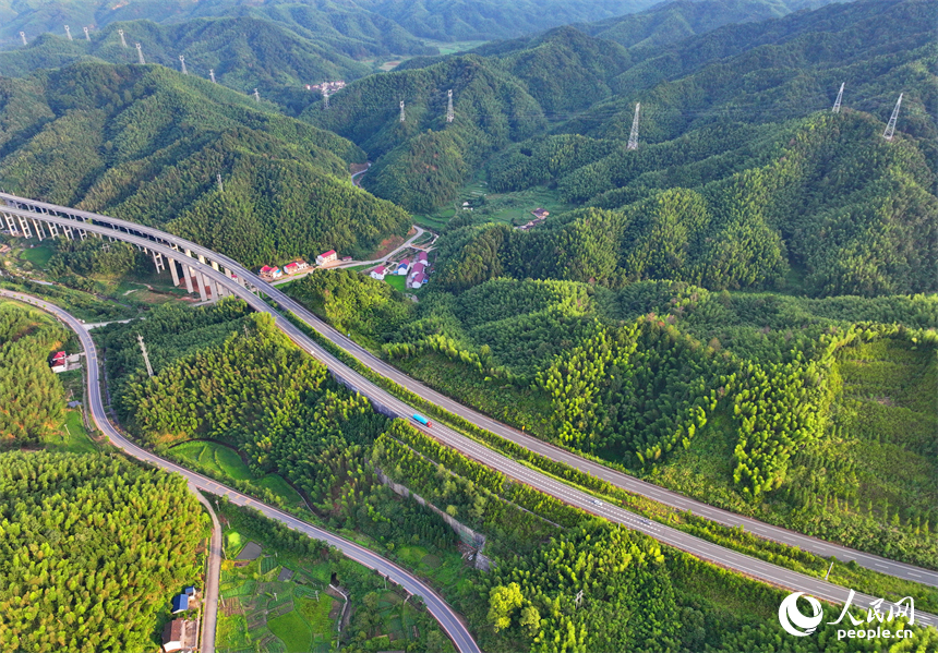 撫州市資溪縣嵩市鎮，撫（州）至吉（安）高速公路如同銀龍蜿蜒穿梭于蒼翠的崇山峻嶺間，與田園、村落相映成景。人民網 朱海鵬攝
