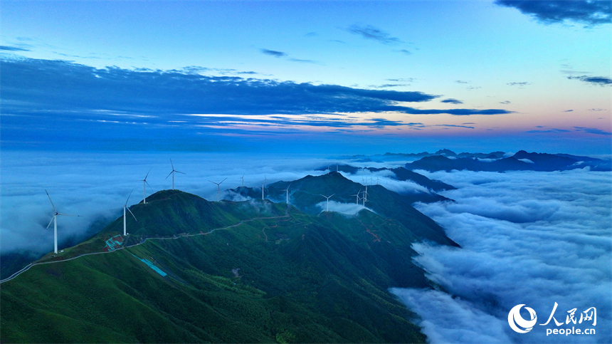 贛州市上猶縣雙溪草山云蒸霞蔚，一臺臺風力發電機迎風旋轉，與延綿群山相映成景，壯美如畫。人民網 朱海鵬攝
