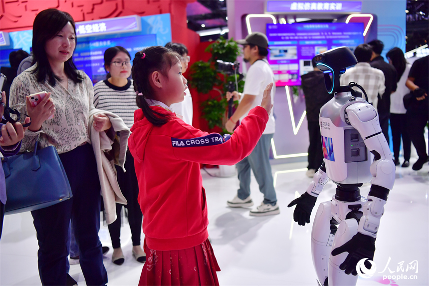 一位小朋友正在與人形機器人互動。人民網記者 時雨攝