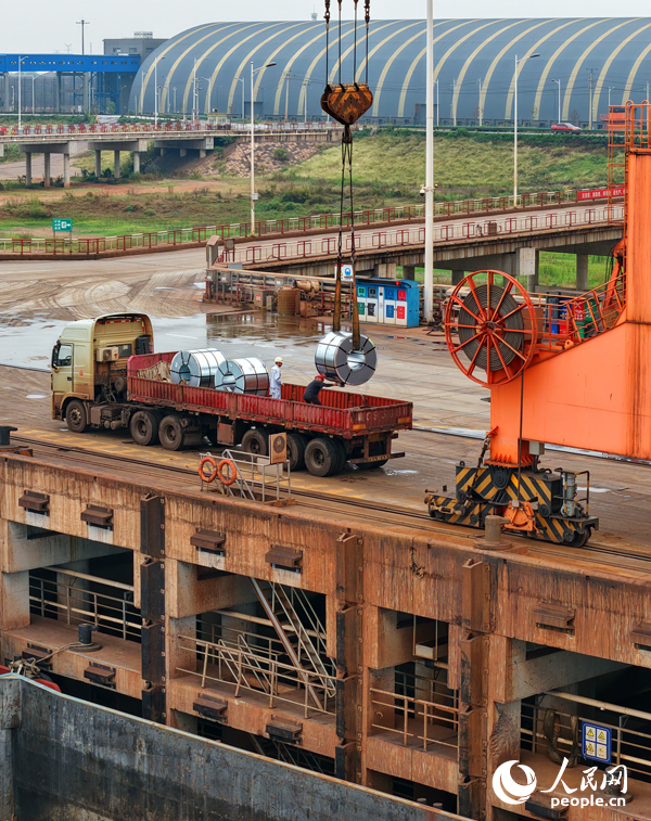 在姚灣綜合碼頭，運輸貨物的車輛往來穿梭，起重機裝卸作業有序進行。人民網 朱海鵬攝