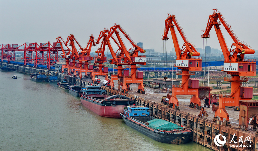 在姚灣綜合碼頭，運輸貨物的車輛往來穿梭，起重機裝卸作業有序進行。人民網 朱海鵬攝