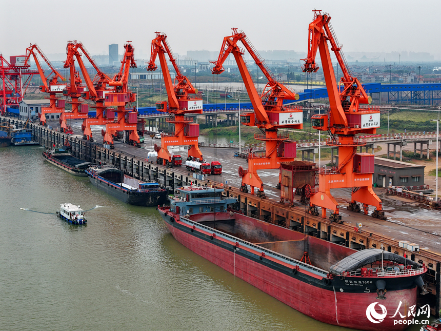 在姚灣綜合碼頭，運輸貨物的車輛往來穿梭，起重機裝卸作業有序進行。人民網 朱海鵬攝